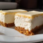 Two creamy no-bake lemon dessert squares with crumb crust on white plate.